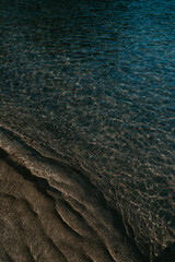 A relaxing scene of sun glistening in turquoise and emerald blue water in Rhodes, Greece. Rocks, waves, reflections, greenery, beach, sand