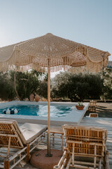 The relaxing scene of a swimming pool area, sun umbrella, trees and loungers at sunset in Rhodes Island, Greece