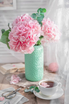 Composition with tea mug and beautiful pink flowers hydrangeas in vase