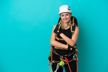 Young caucasian rock climber woman isolated on blue background pointing to the side to present a product