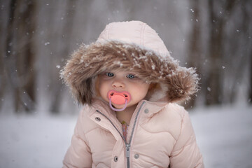 Female young child outdoors with pacifier in winter wearing a pi