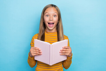 Portrait of astonished clever schoolkid open mouth hands hold book isolated on blue color background