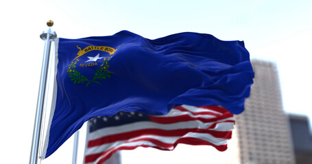 The flags of the Nevada state and United States of America waving in the wind. Democracy and...