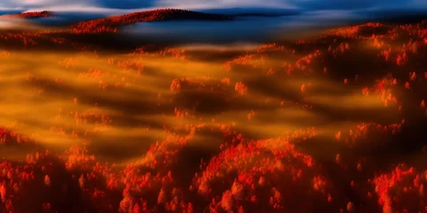 Luftaufnahme des Bergwaldes in niedrigen Wolken bei Sonnenaufgang im Herbst. Hügel mit roten und orangefarbenen Bäumen im Nebel im Herbst. Schöne Landschaft mit Berg, Nebelwald, Sonnenstrahlen. Blick von oben auf den Wald © The 2R Artificiality