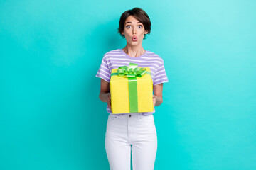 Photo of excited impressed positive girl with bob hairstyle wear striped t-shirt hold present isolated on turquoise color background