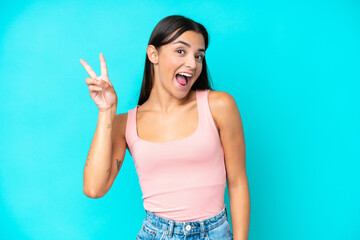 Young caucasian woman isolated on blue background smiling and showing victory sign