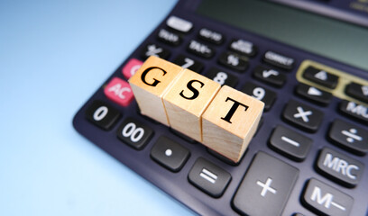 Fototapeta na wymiar GST or Goods and Services Tax by letters on wooden beads or blocks and calculating GST with calculator.