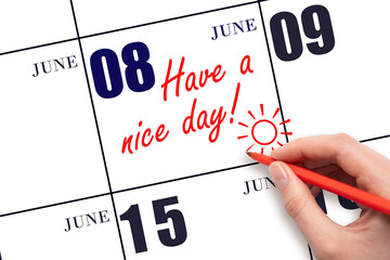 The hand writing the text Have a nice day and drawing the sun on the calendar date June 8