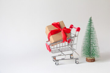 Gift box with miniature shopping cart on white background.