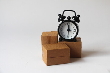 cardboard boxes and black alarm clock on white background, fast shipping. transportation speed. storage time in the warehouse. delayed delivery. quick carriage.