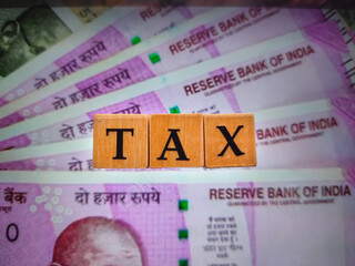 Fototapeta premium TAX by letters on wooden beads or block with 2000 rupee notes background.