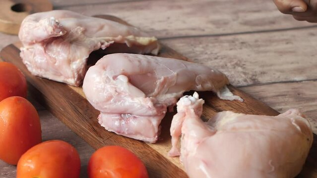 precessing raw chicken breast on a chopping board 