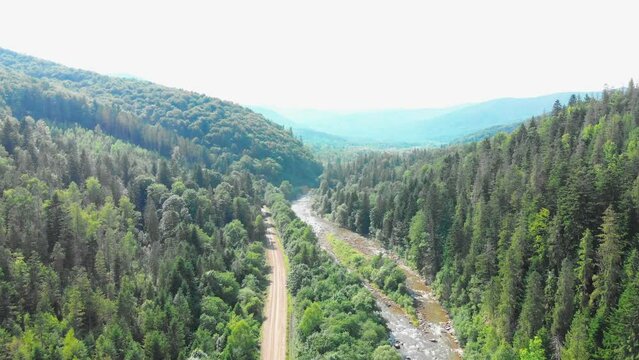 The truck is traveling along a mountain road on tourist route. A tourist trip through Ukrainian Carpathians in the summer. Big green tourist car Zil. Rest in nature among the river and green forests.