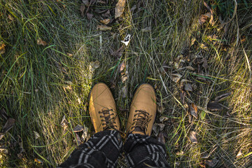 Men's feet in shoes on the grass. Walk in autumn nature.