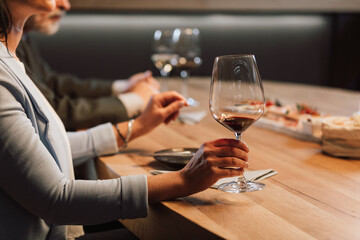 People drinking wine and eating cold cut meat in a wine cellar.