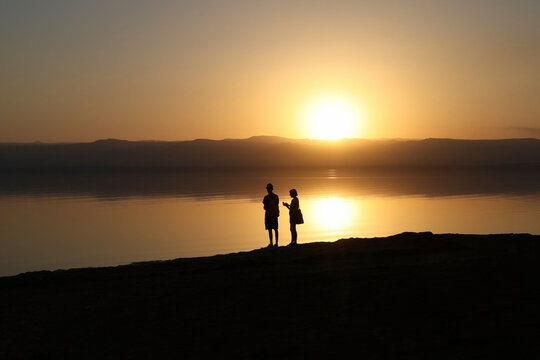 silhouette of couple on dead sea shore at sunset