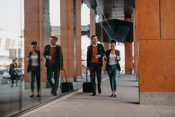 Obraz premium Business man and business woman talking and holding luggage traveling on a business trip, carrying fresh coffee in their hands.Business concept