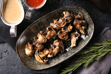 Grilled vegetables. Fried mushrooms with herbs on a plate, red and white sauces, ketchup, spices. Rosemary on a dark table. Turkish cuisine, dish. Vegetable garnish. Background image, copy space