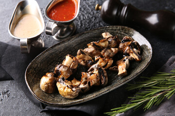 Grilled vegetables. Fried mushrooms with herbs on a plate, red and white sauces, ketchup, spices. Rosemary on a dark table. Turkish cuisine, dish. Vegetable garnish. Background image, copy space