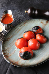 Grilled vegetables. Fried tomatoes with herbs on a plate, red and white sauces, ketchup, spices. Rosemary on a dark table. Turkish cuisine, dish. Vegetable garnish. Background image, copy space