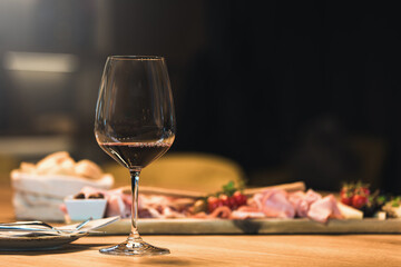 People drinking wine and eating cold cut meat in a wine cellar.