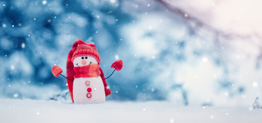 Little knitted snowman on the white snow on blue background.