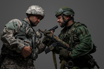 Studio shot of disagreements of russia and nato soldiers dressed in camouflage uniforms.