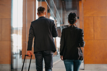 Fototapeta premium Business man and business woman talking and holding luggage traveling on a business trip, carrying fresh coffee in their hands.Business concept