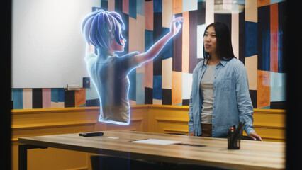 An avatar of a girl gives presentation to an asian woman through an abstract hologram screen in...