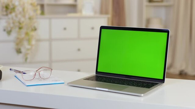 Laptop With Green Mock-up Screen On Desk In Room