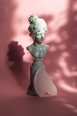 Rose quartz gouache scraper on a pink background with hard shadows. Natural stone face massager, lymphatic drainage massage cosmetics, Chinese therapy,  hard shadows