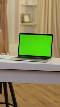 Laptop With Green Mock-up Screen On Desk In Room. Vertical Video