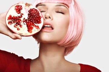 Girl with pomegranate. Pink hair. Makeup. - 536377940