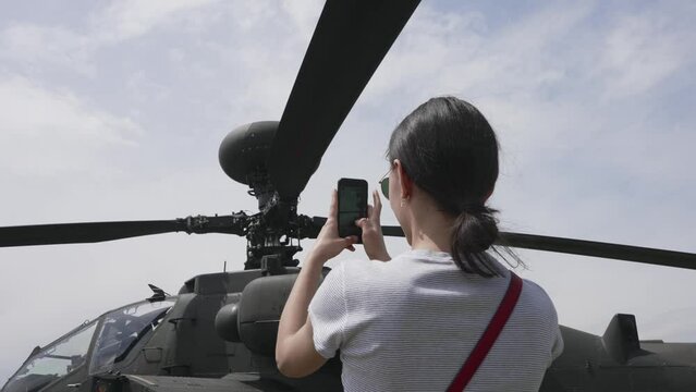 Young woman take pictures from Apache attack helicopter chopper on display at the Army Aviation Centre