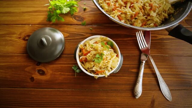 Braised cabbage with carrots, onions and herbs in a ceramic bowl