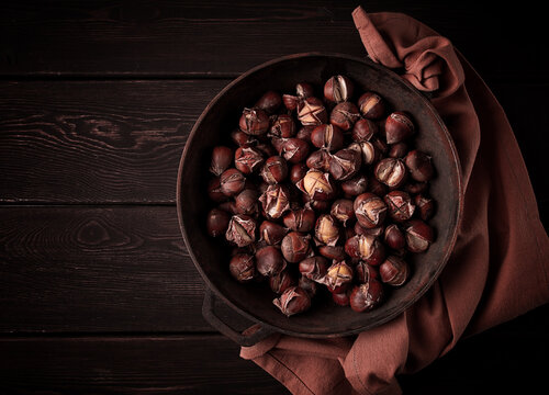 Roasted chestnuts, in an iron pan, wooden table, top view, no people, rustic style,
