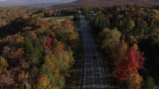 The drone shot tilts up to reveal the pretty countryside of Stowe, Vermont as the sunsets from behind.  The autumn air is cool and crisp.  The fall foliage is on fire.