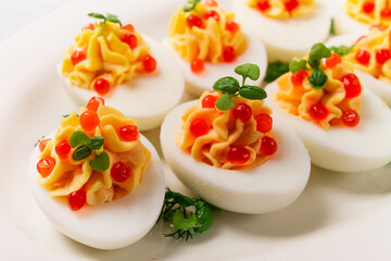 Stuffed eggs, with red caviar, micro greenery, Snack, on a white plate, top view, close-up, no people,