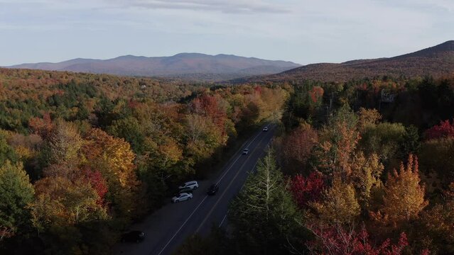 An aerial drone shot in Stowe, Vermont over by Smugglers Notch.  The drone heads towards the busy country road.