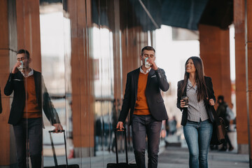 Business man and business woman talking and holding luggage traveling on a business trip, carrying fresh coffee in their hands.Business concept