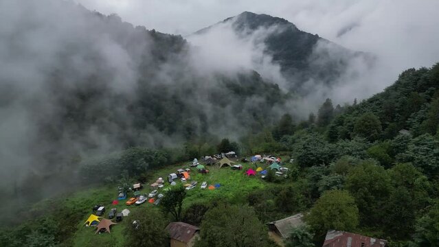 Drone shot of a camping in jungle visible through clouds, North of Iran, Gilan
