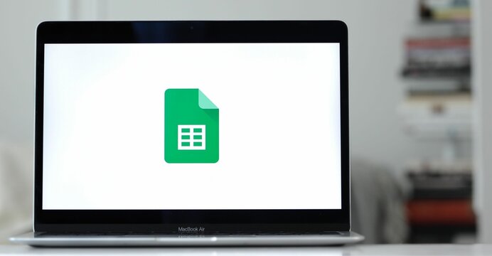 Logo design of google sheets on a laptop screen in blurred background