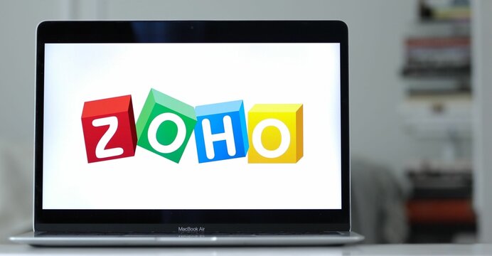 Logo design of Zoho on a laptop screen in blurred background