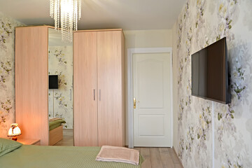 Bedroom interior with wardrobe and TV on the wall