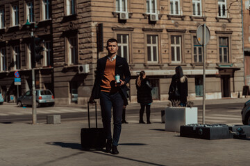 Going to airport terminal. Confident businessman traveler walking on city streets and pulling his suitcase drinking coffee and speaking on smartphone