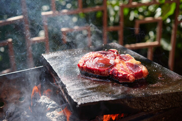 Raw beef burger steak on grill. Cutlet meat placed on grill stone with fire.
