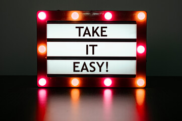 Lightbox with red lights in dark room with phrase- take it easy.