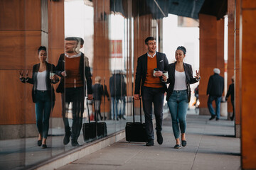 Business man and business woman talking and holding luggage traveling on a business trip, carrying fresh coffee in their hands.Business concept