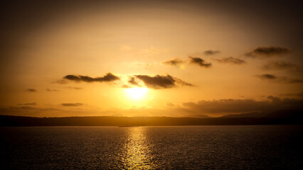 Sunset from a cruise ship near coast of Spain - view of mountains, water, clouds and sun setting.