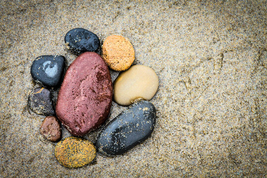 Colorful stones gathered on the on Oregon Coast Shore - positioned on the sandy beach to create a background image